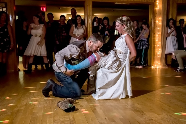 A groom grabbing the garter off his bride's leg with his teeth.