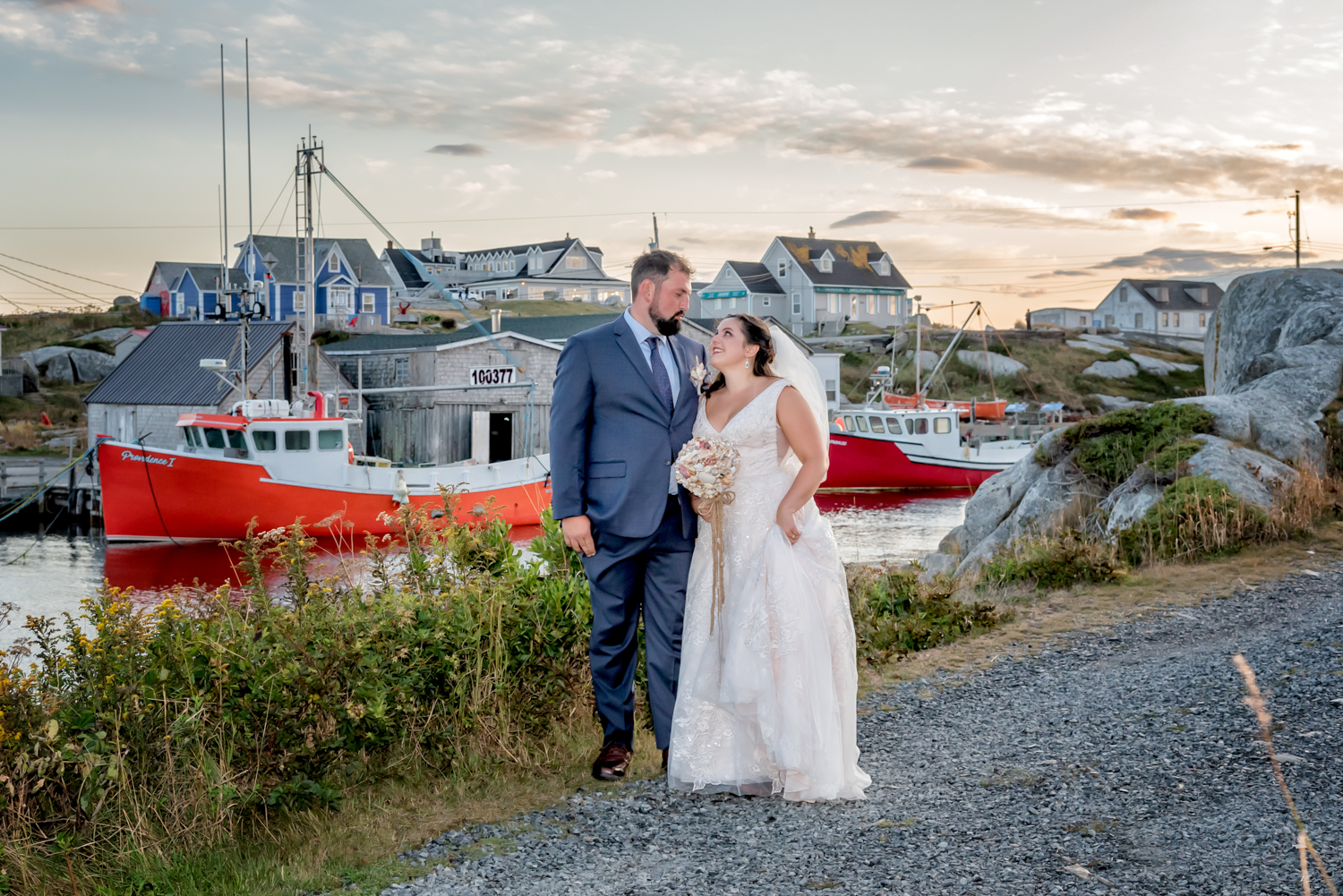 A bride and groom pose for wedding photos infront of the boats at Peggys Cove in Nova Scotia.