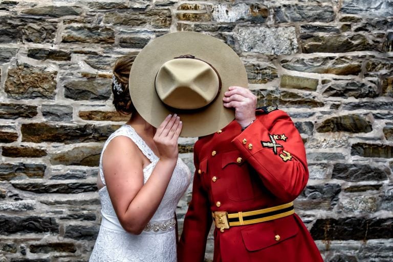 The bride and groom hiding behind an RCMP hat in Halifax, Nova Scotia.