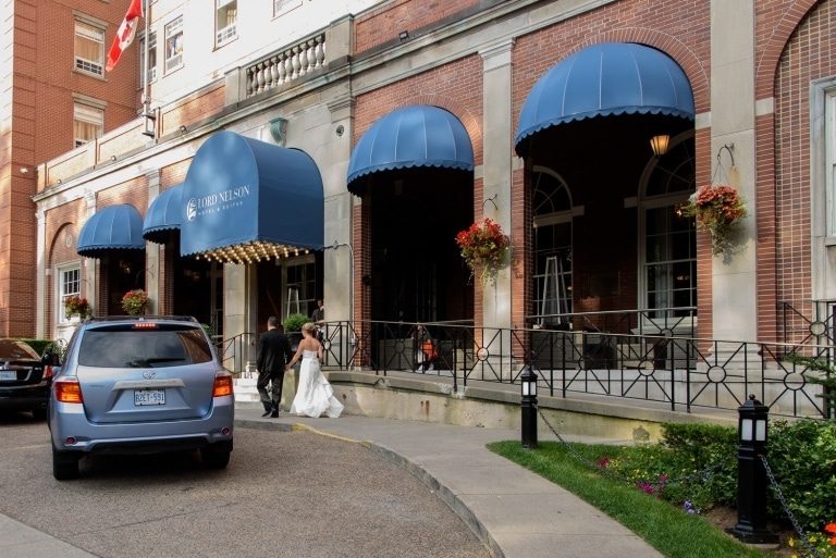 The bride and groom walking outside the front of their hotel l in Halifax, NS.