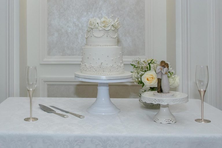 An elegant ivory wedding cake with bride and groom figurine at a Lord Nelson Hotel wedding.