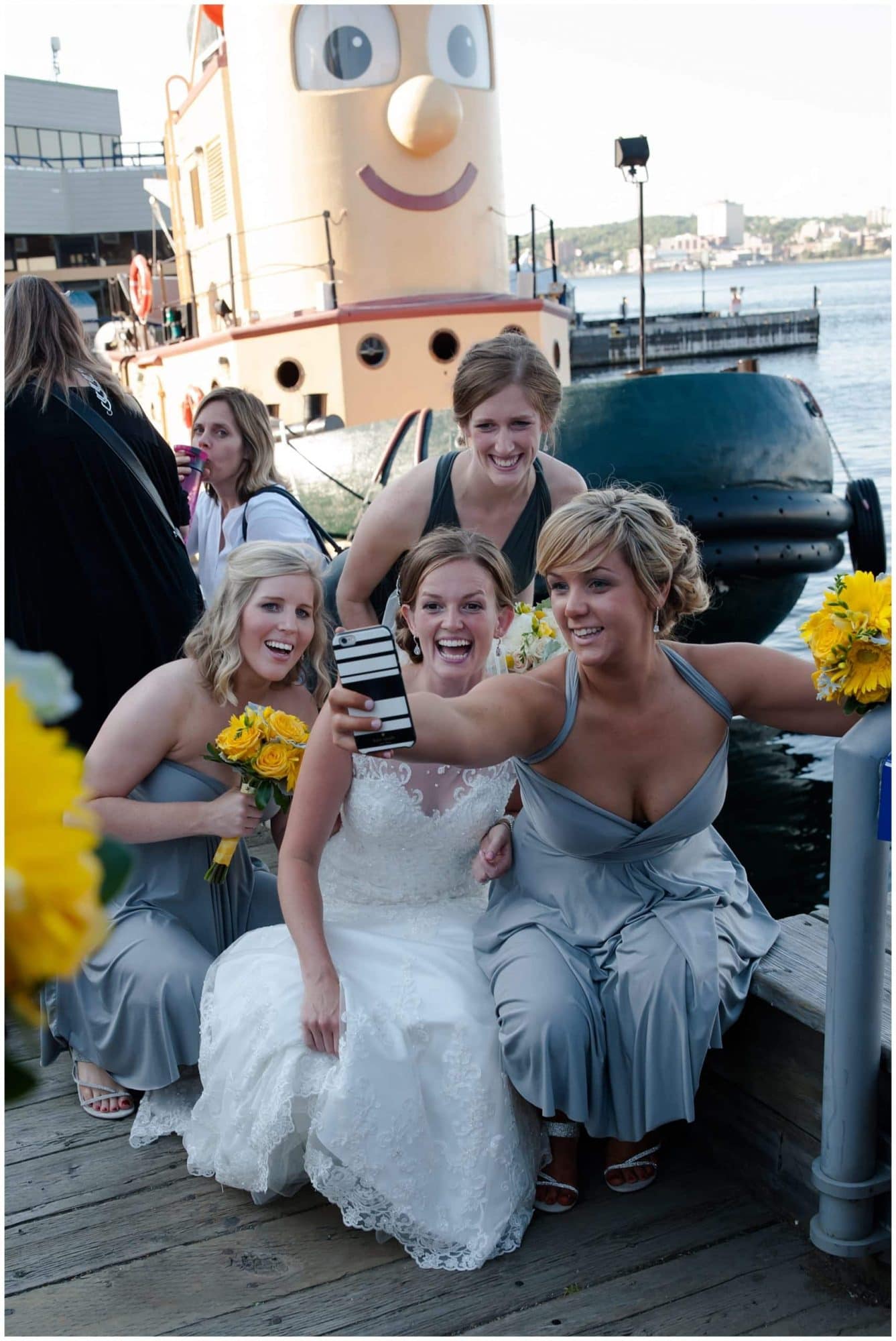 The bride snaps a selfie of her and her bridesmaids infront of Theodore the tug boat in Halifax, NS.