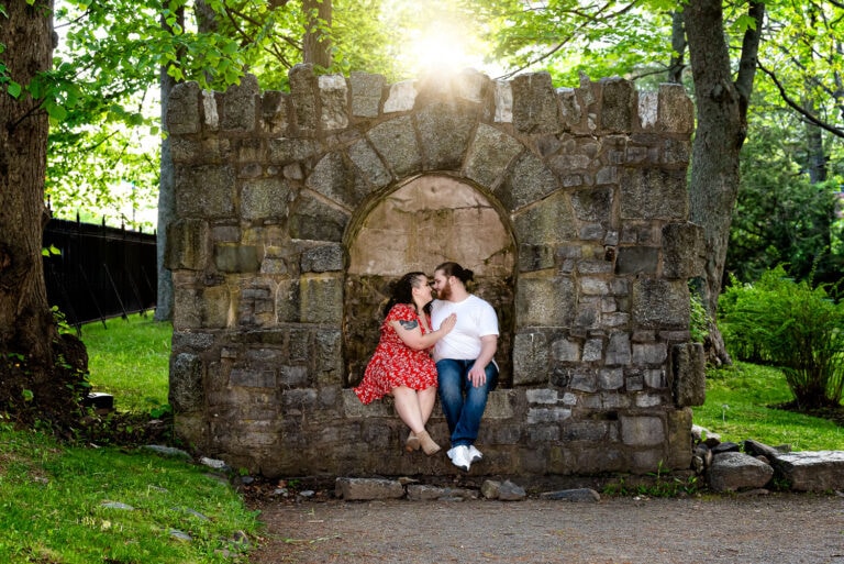 A couple in love pose for their engagement photos at the Halifax Public Gardens by sitting in the small castle.