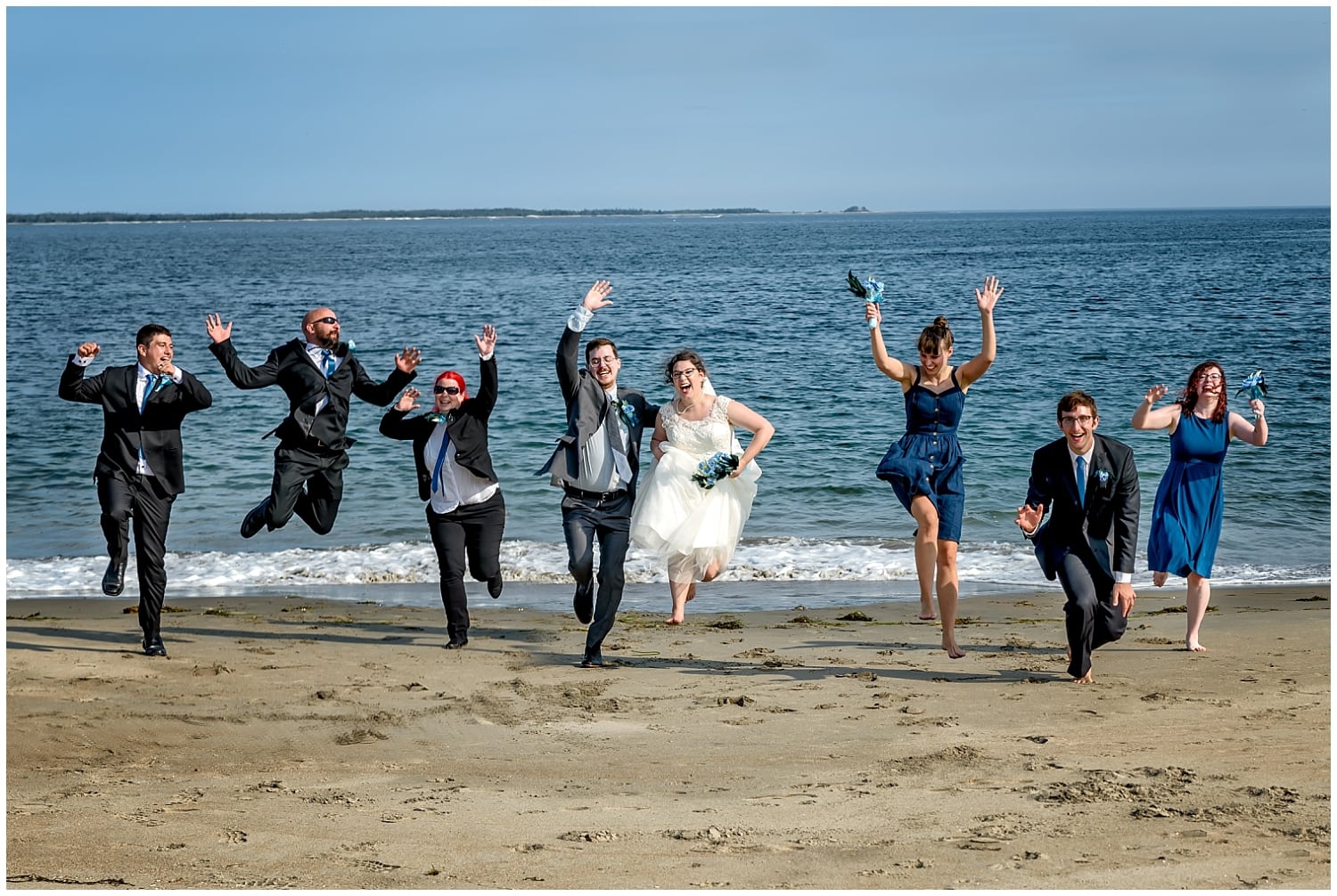 The entire wedding party run across the beach and jump into the air during a beach wedding in Green Bay NS.
