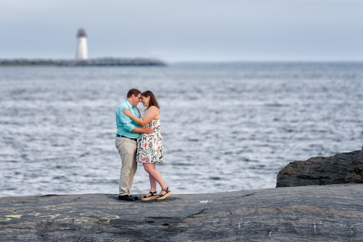 A newly engaged couple embrace infront of a lighthouse for their engagement photos at Point Pleasant Park in Halifax, NS.