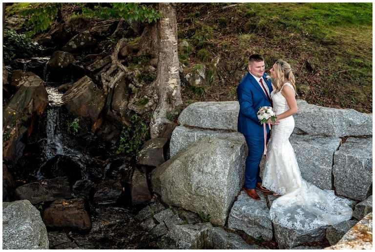 The bride and groom pose for their wedding photos by a waterfall in Sir Sandford Fleming Park in Halifax, NS.