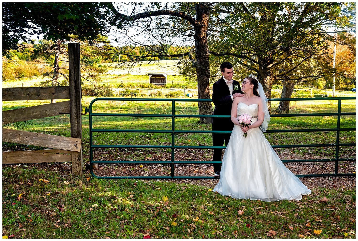 A bride and groom gaze at each other by a fence at the Kinley Farm in Lunenburg, NS.