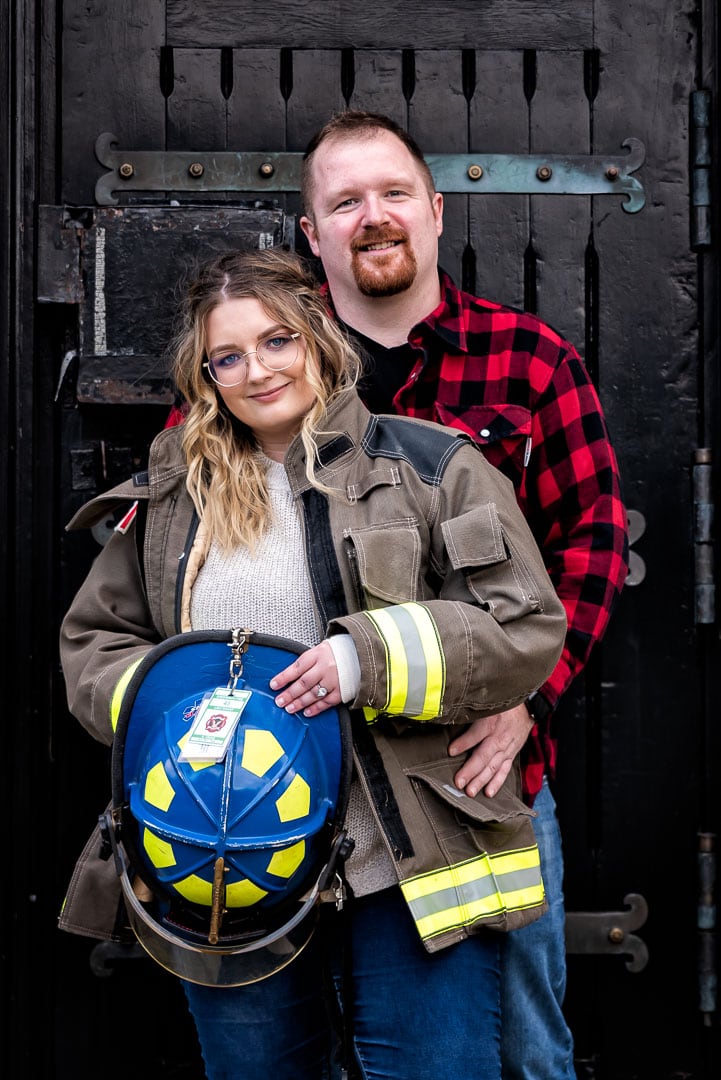 A cute firefighting couple pose in fireman gear for their engagement session at the Dingle Tower in Halifax, NS.