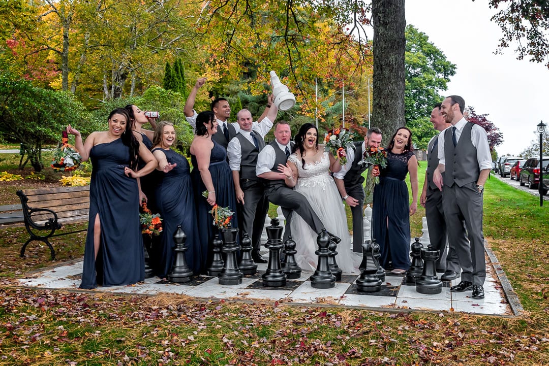 The bride and groom pose with their wedding party for wedding photos on a giant chessboard at the Digby Pines Resort in NS.