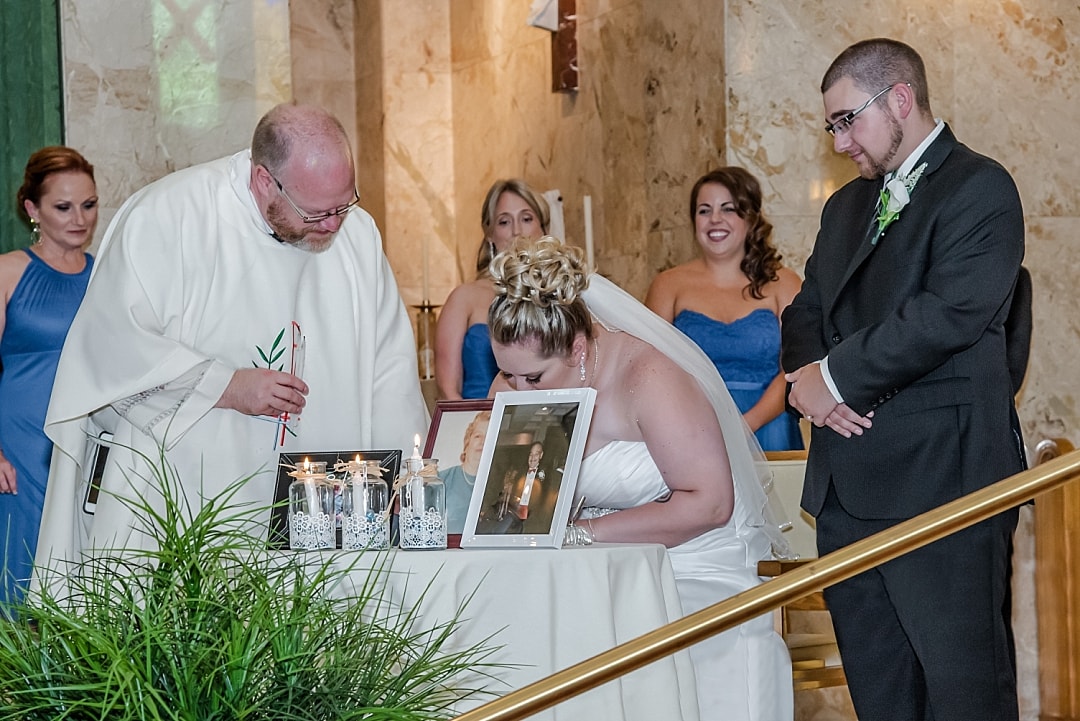 The bride and groom sign their marriage certificate surrounded by candles lit for loved ones who are no longer with them to remember that they are still there at heart.