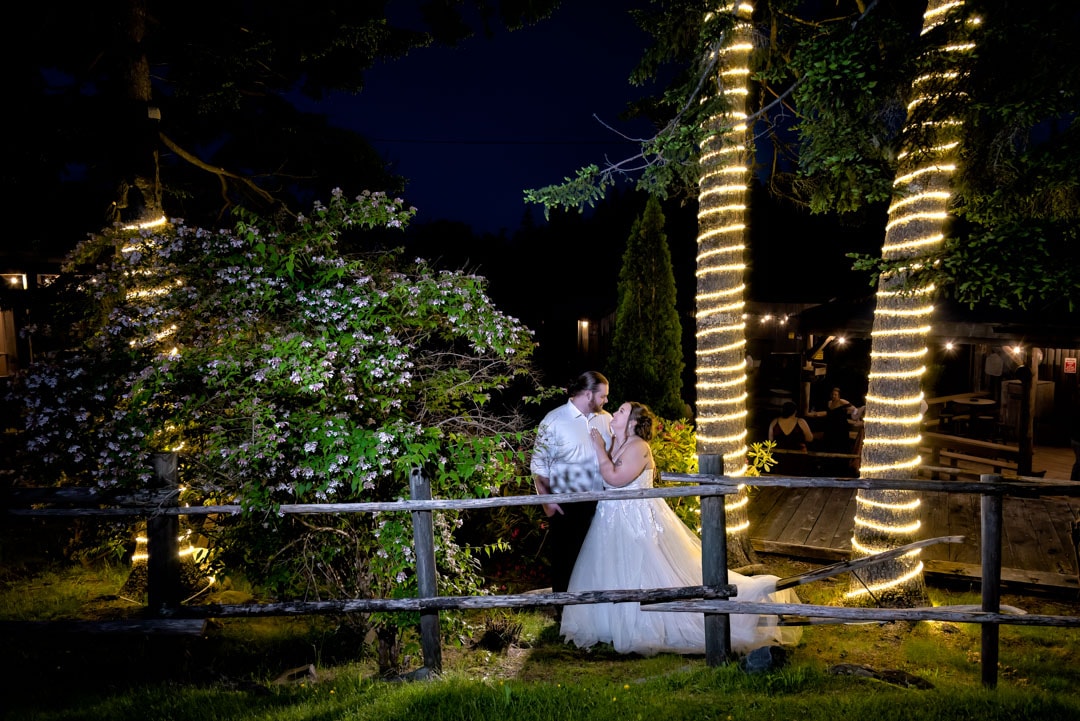 Bride and groom stand under lit up trees for wedding photos at night at Hatfield Farm in Halifax, NS.