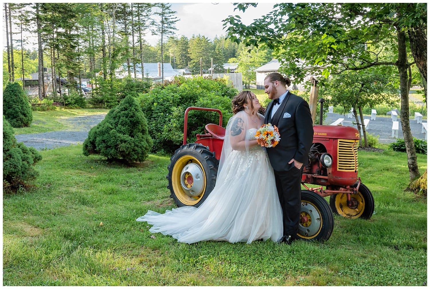 The bride and groom pose for wedding photos in front of a rustic tractor during their wedding at Hatfield Farm in Halifax, NS.