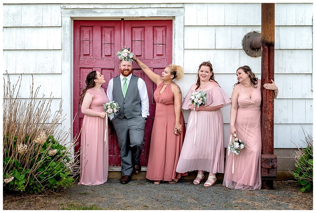 The groom poses with the bridesmaids for wedding photos at Healy Farm in NS.