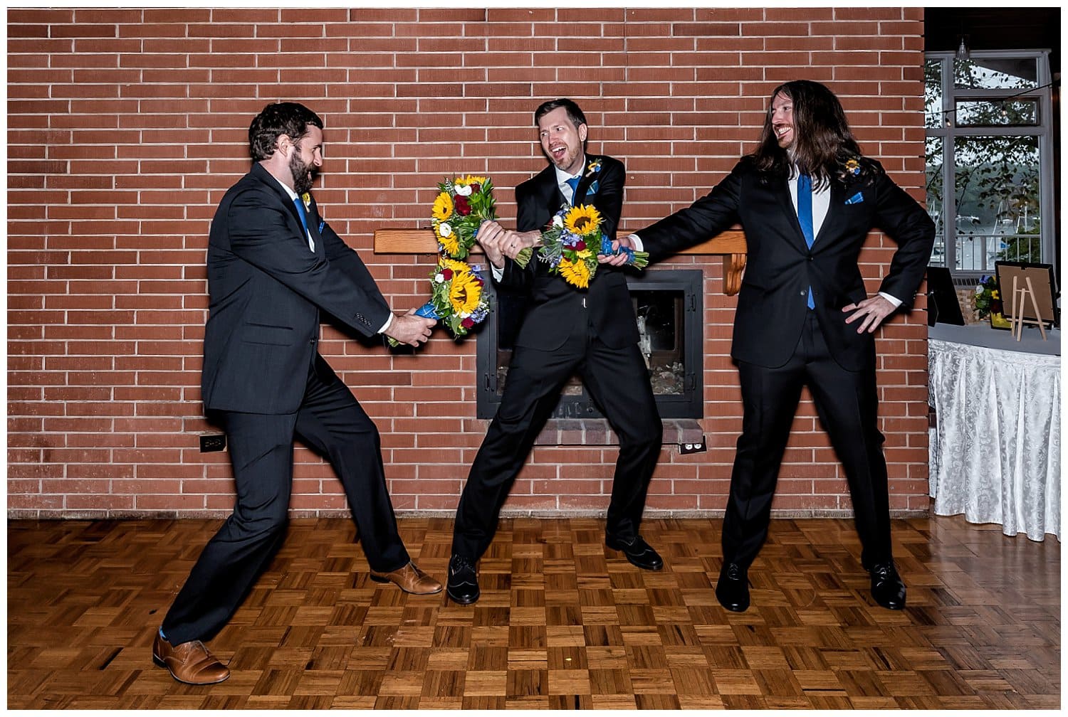 The groom and his groomsmen fight with sunflower bouquets during wedding photos at Saraguay House.
