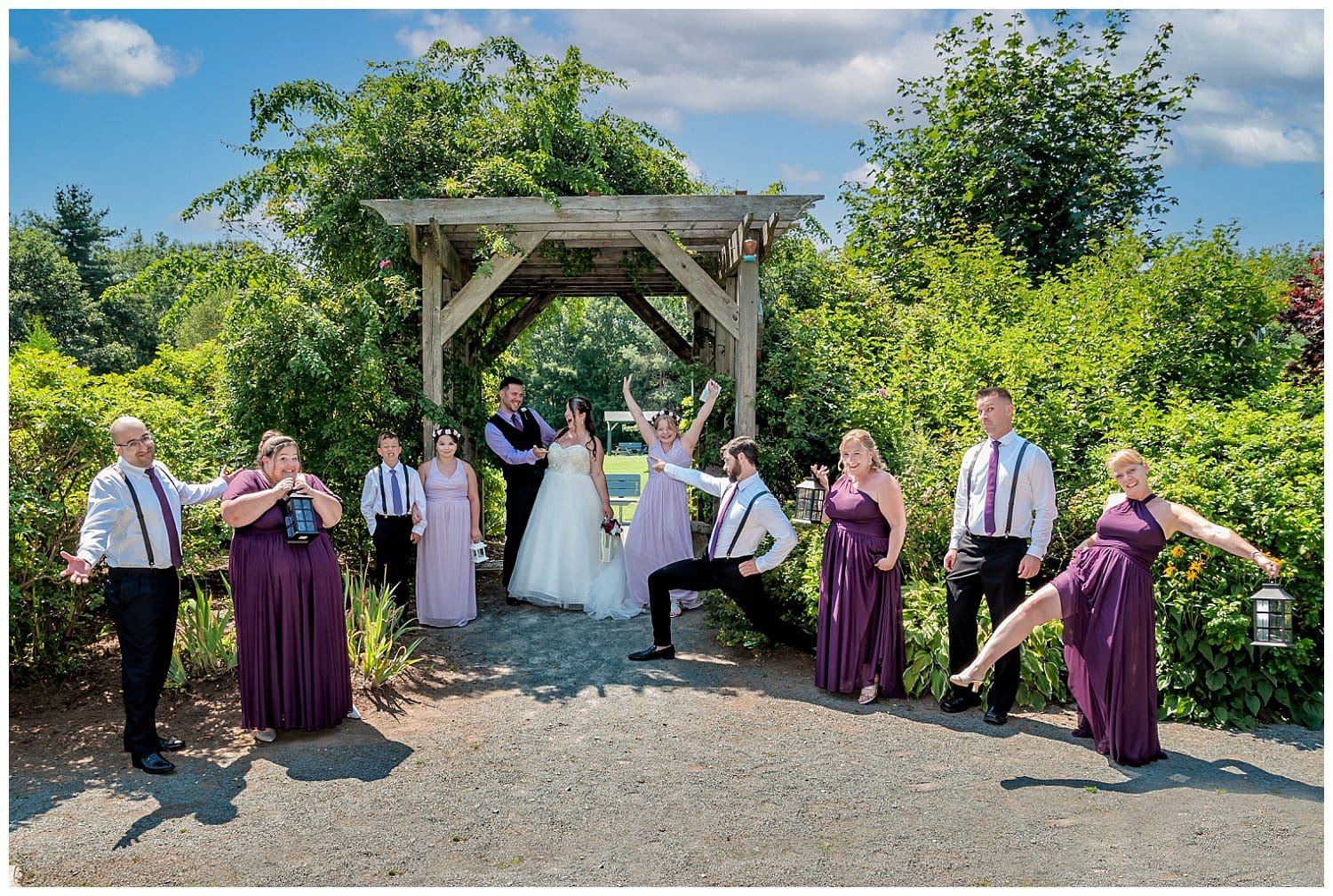 The wedding party pose with the bride and groom under a trellis at Acadia Park in Sackville NS.