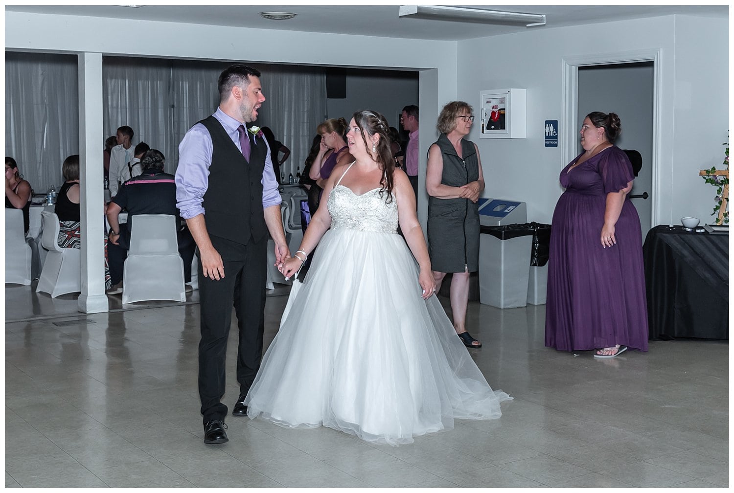 The bride and groom walk towards the dance floor for their first dance at the Sackville Lions Club in NS.