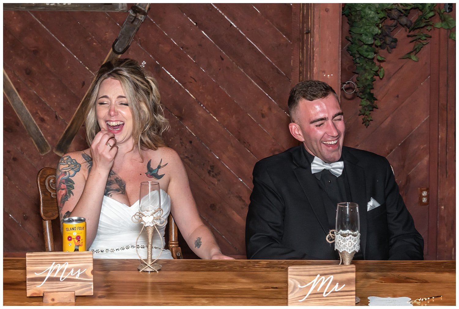 The bride and groom laugh during parent speeches at their wedding reception in Hatfield Farm's barn.