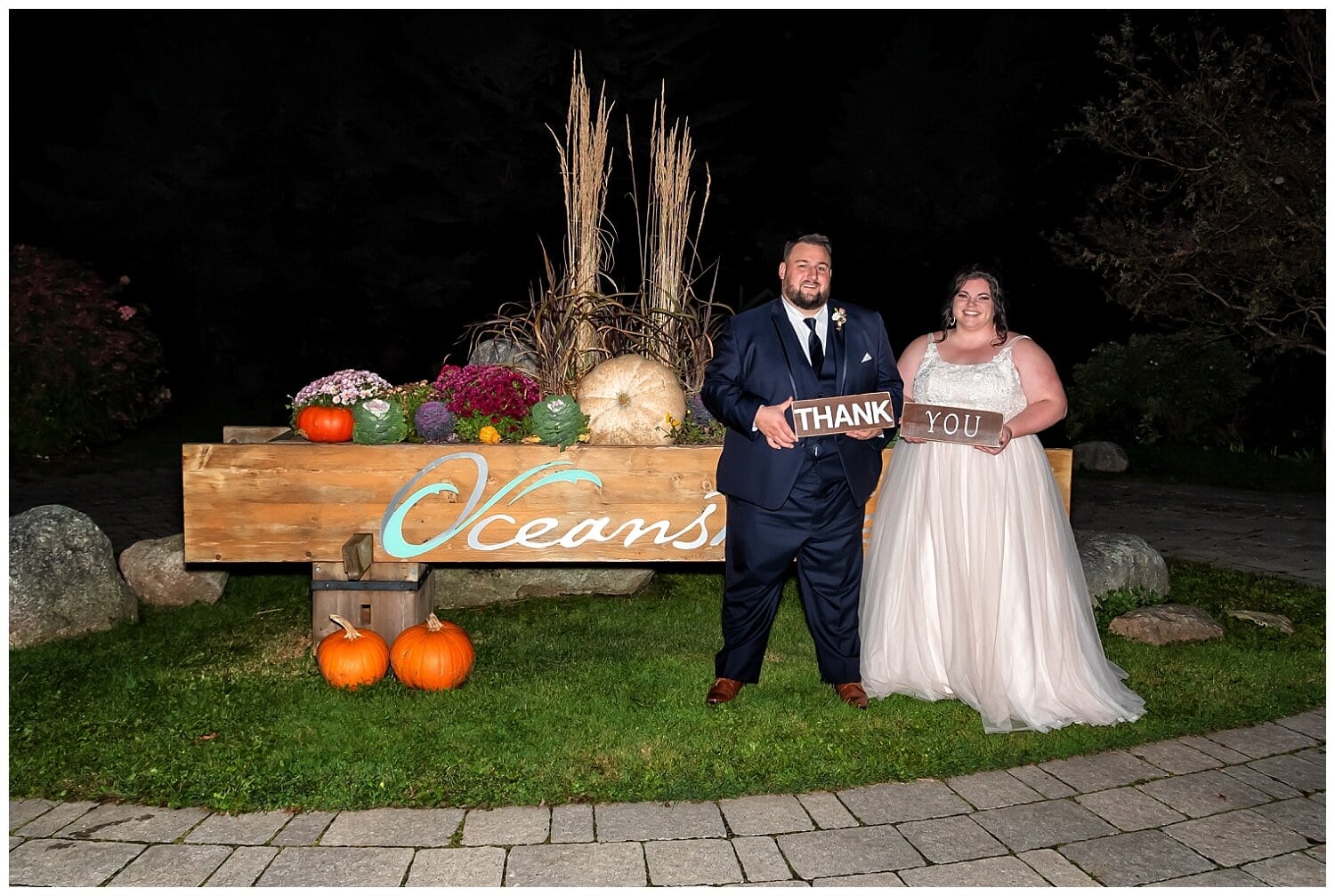 A bride and groom hold thank you signs during their wedding reception at Oceanstone.