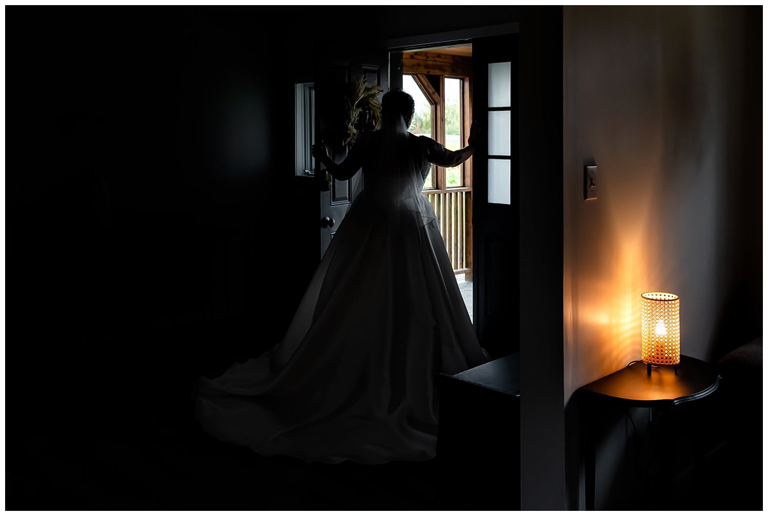 The bride poses at the front door in silhouette while getting ready for her wedding day in an Airbnb in Windsor NS.