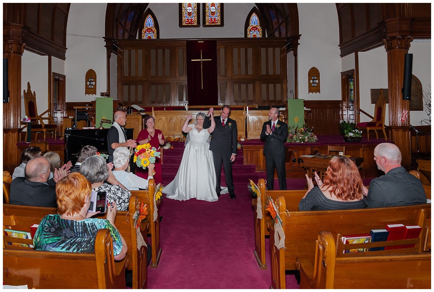 The wedding party, bride and groom stand at the alter of the church during their wedding ceremony in Windsor NS.