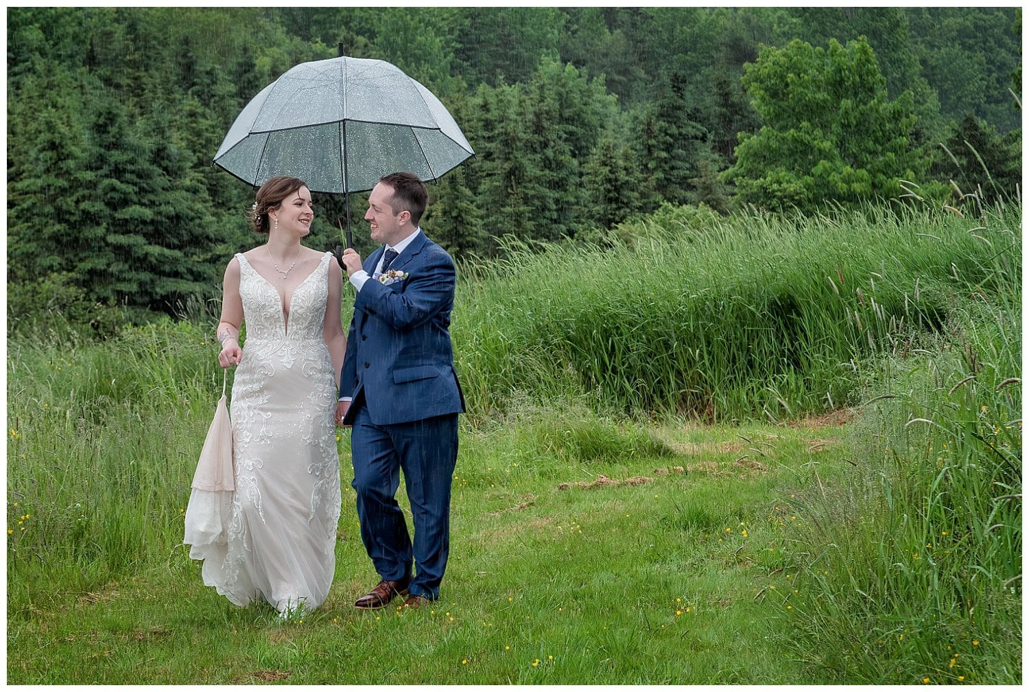 The bride and groom walk together for wedding photos in the rain at Parkers Barn in Hopewell NS.