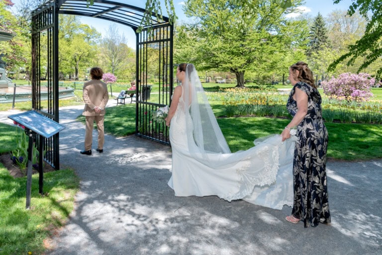 Bride in a lace gown and groom in a tan suit during their first look in a park setting in the Halifax Public Gardens.