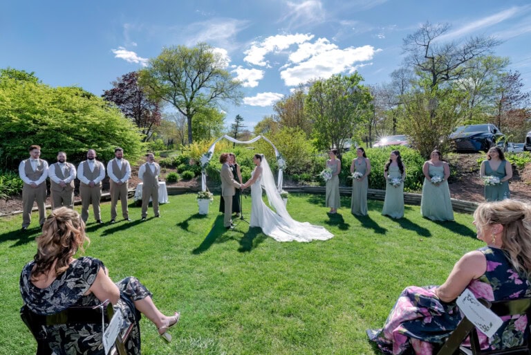 Bride and groom standing under a floral ceremony arch during their outdoor wedding at Ashburn Golf Club in Halifax.