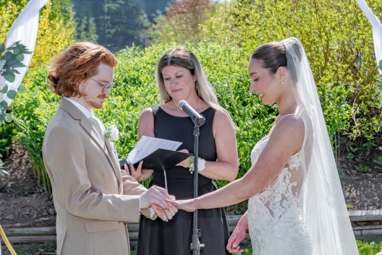 Outdoor ring exchange beneath a floral arch during Megan and Kage’s Ashburn Golf Club wedding in Halifax.