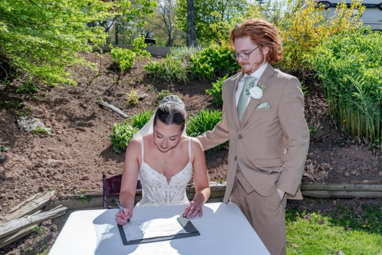 Bride signing the marriage license at Ashburn Golf Club in Halifax while the groom stands beside her.