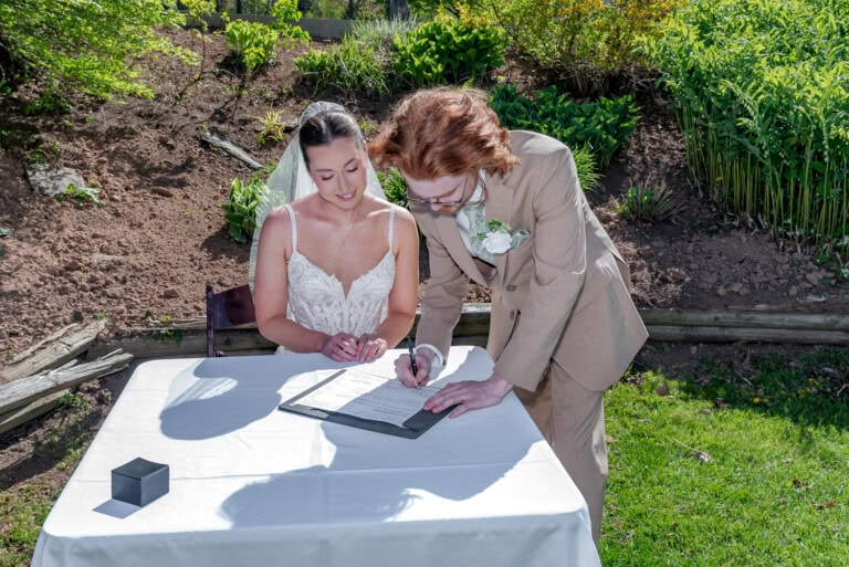 Bride and groom singing their marriage certificate in a garden setting at the Ashburn Golf Club in Halifax.