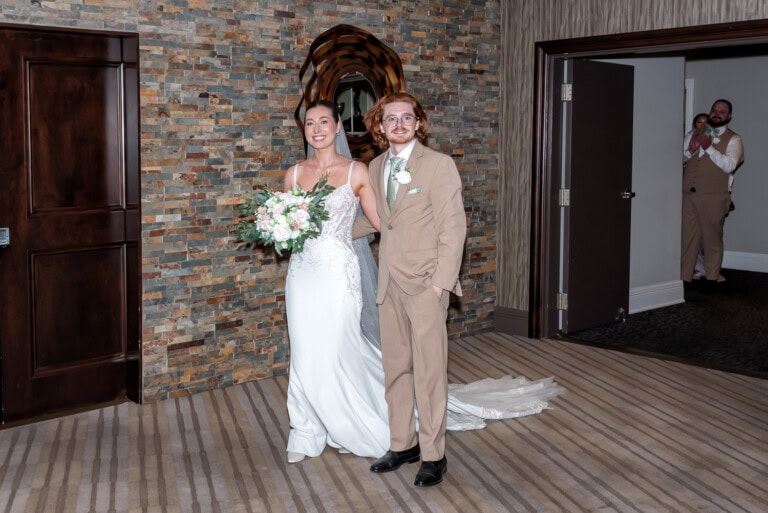 Bride and groom entering their wedding reception at Ashburn Golf Club as guests cheer.