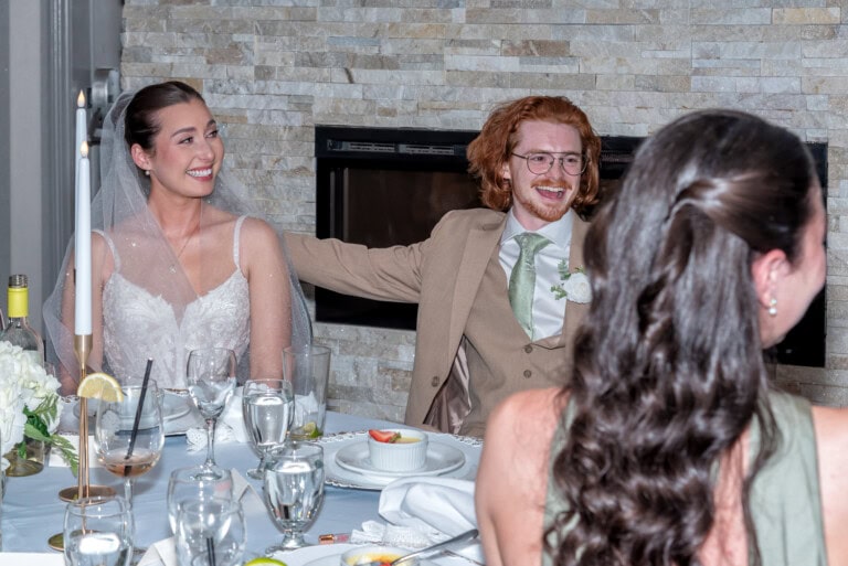 Bride and groom seated at the reception table both reacting emotionally to a speech at Ashburn Golf Club in Halifax.