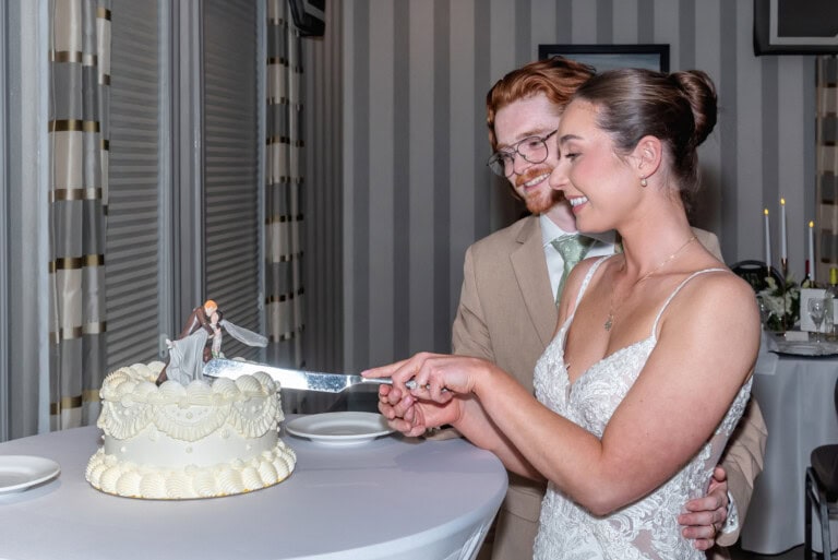 Bride and groom smiling as they cut their wedding cake together at Ashburn Golf Club in Halifax.
