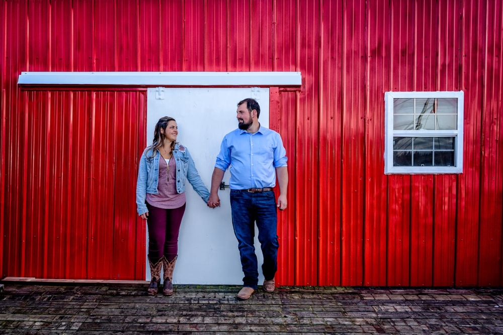 Engagement Portfolio Page A loving couple stand hand in hand infront of their red fishing shack at Peggys Cove, NS.