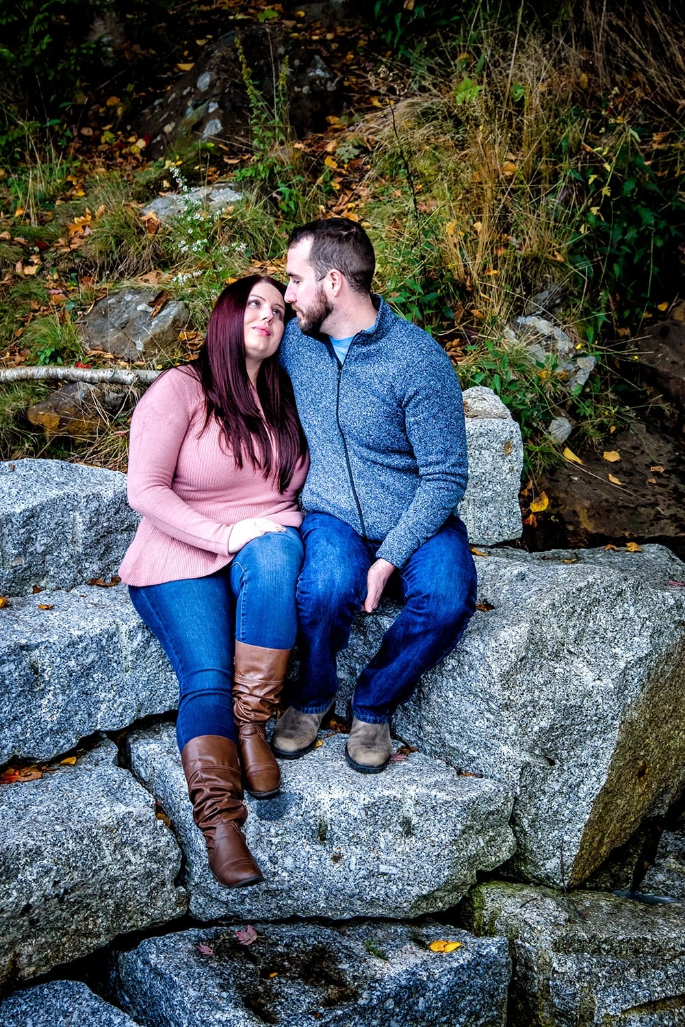 Engagement Portfolio A young couple holding each other by a waterfall during engagement photos at Dingle Park in Halifax, NS.