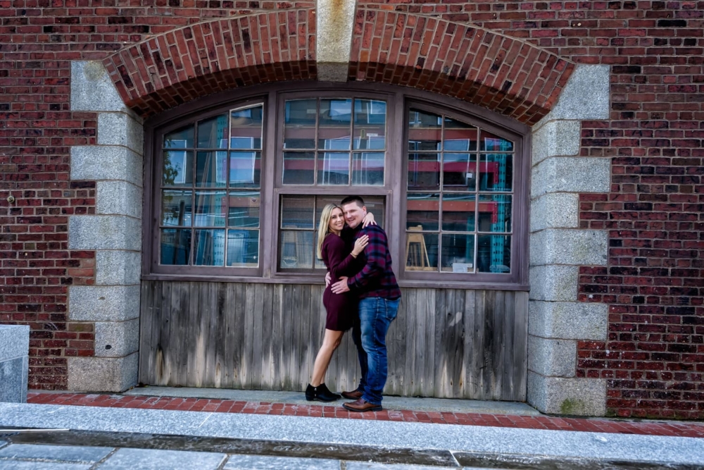 Cute couple in love pose for their engagement photos in downtown Halifax on the waterfront.