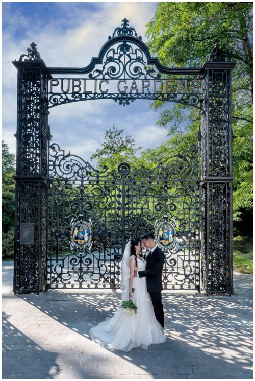 The bride and groom pose for wedding photos in front of the beautiful rod iron gates of the public gardens in Halifax.